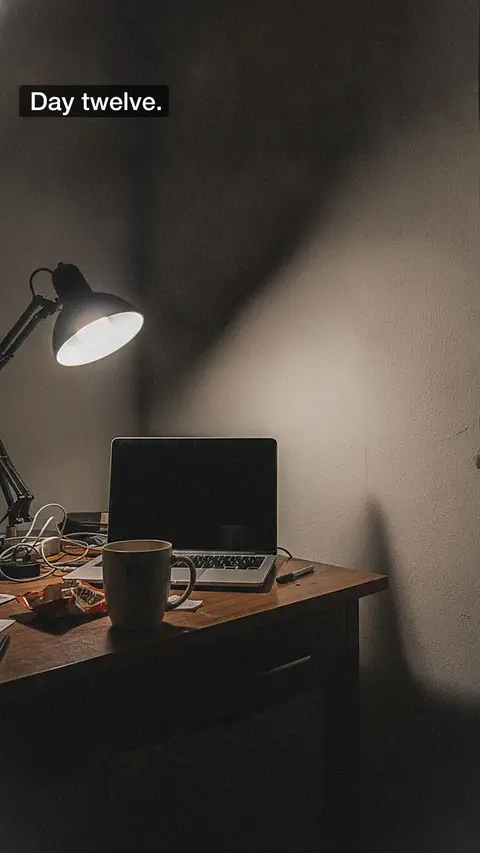 A dark desk under a lamp, captioned "Day twelve."
