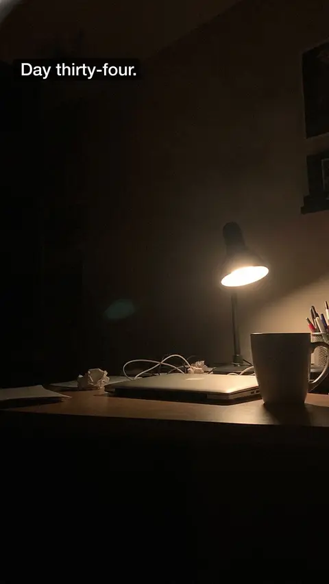 A desk lamp in a dark room, captioned "Day thirty-four."